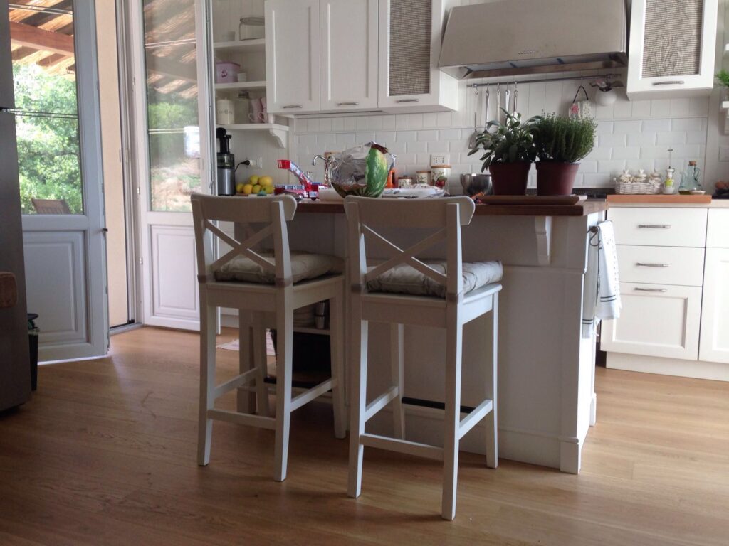 Foto di isola per cucina rivestita in legno e arredamenti per la casa: sedie e mobili bianchi.